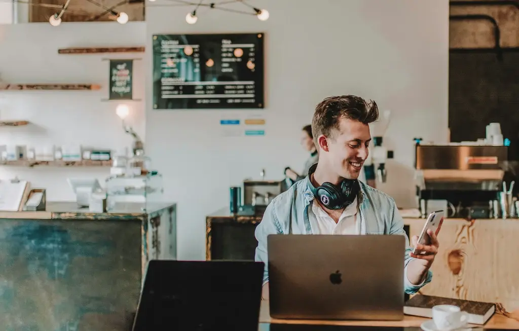 A man working in a laptop with a phone