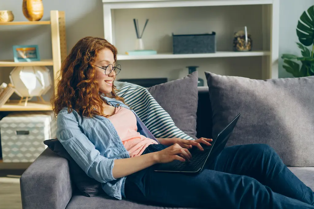 A woman is smiling using a laptop