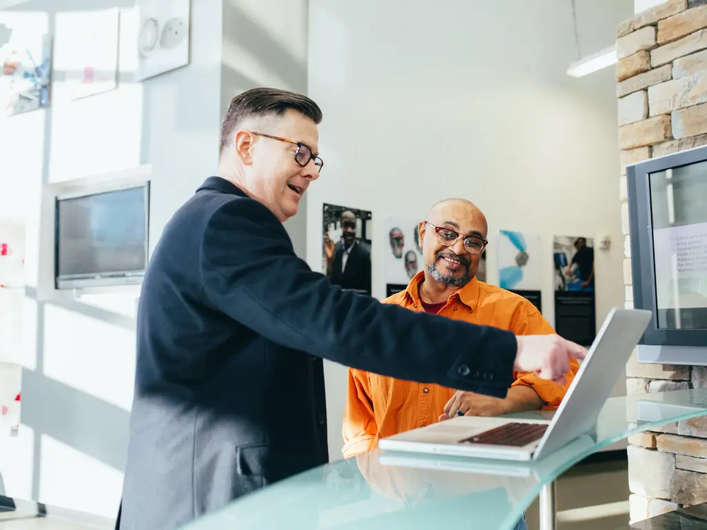 two men looking at sales reports on a laptop