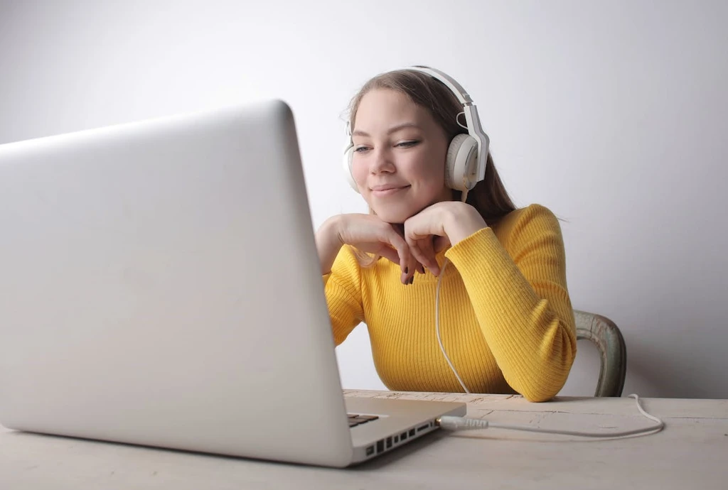 A woman with a headset smiling in front of her laptop